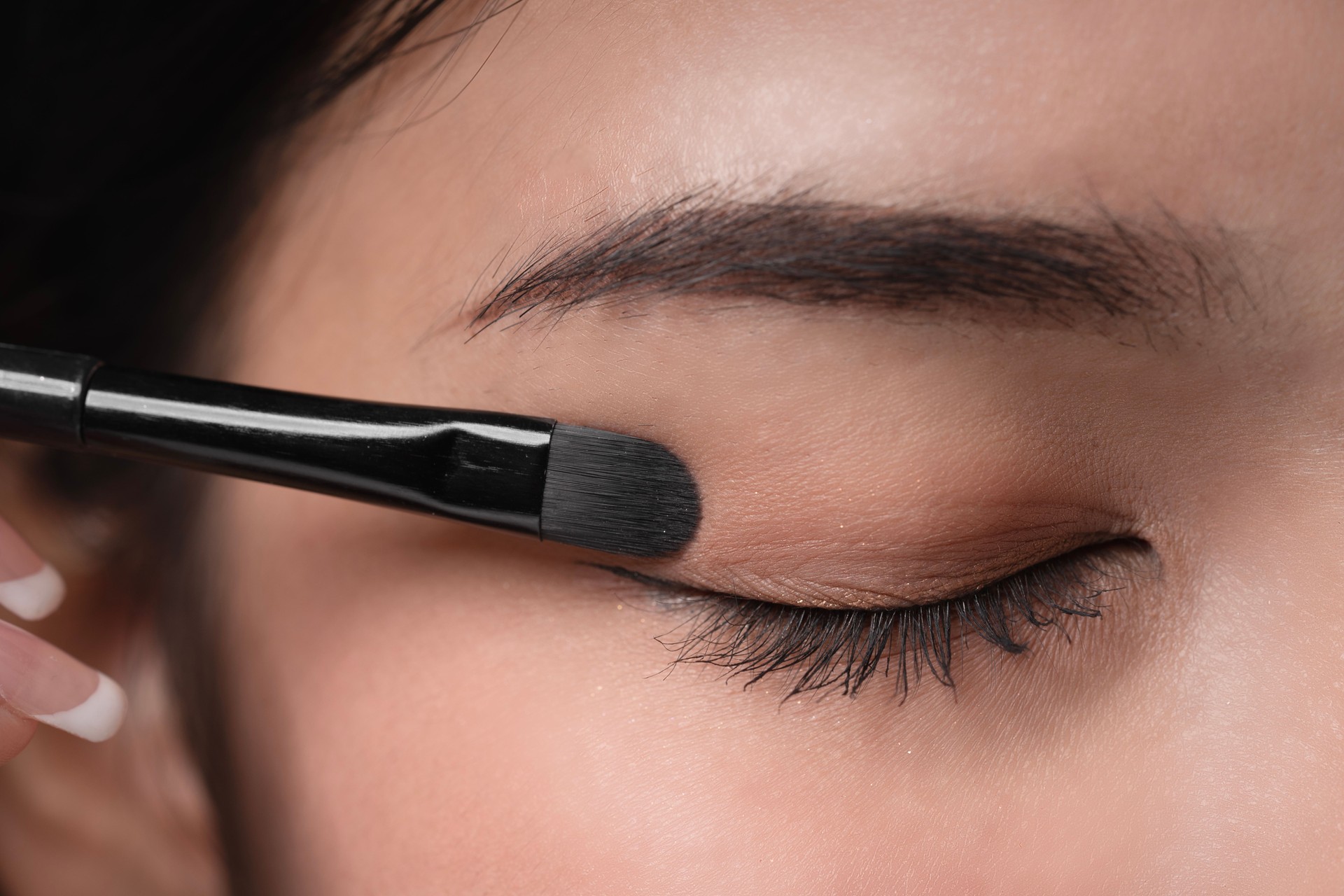 Close-up,Young beautiful asian woman applying makeup eye shadow by brush.